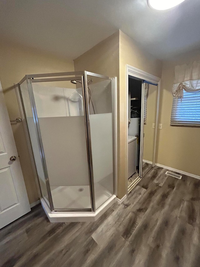 bathroom with a shower with shower door and hardwood / wood-style flooring