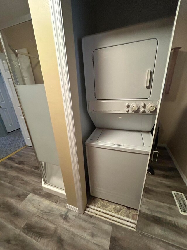 laundry room featuring dark wood-type flooring and stacked washing maching and dryer