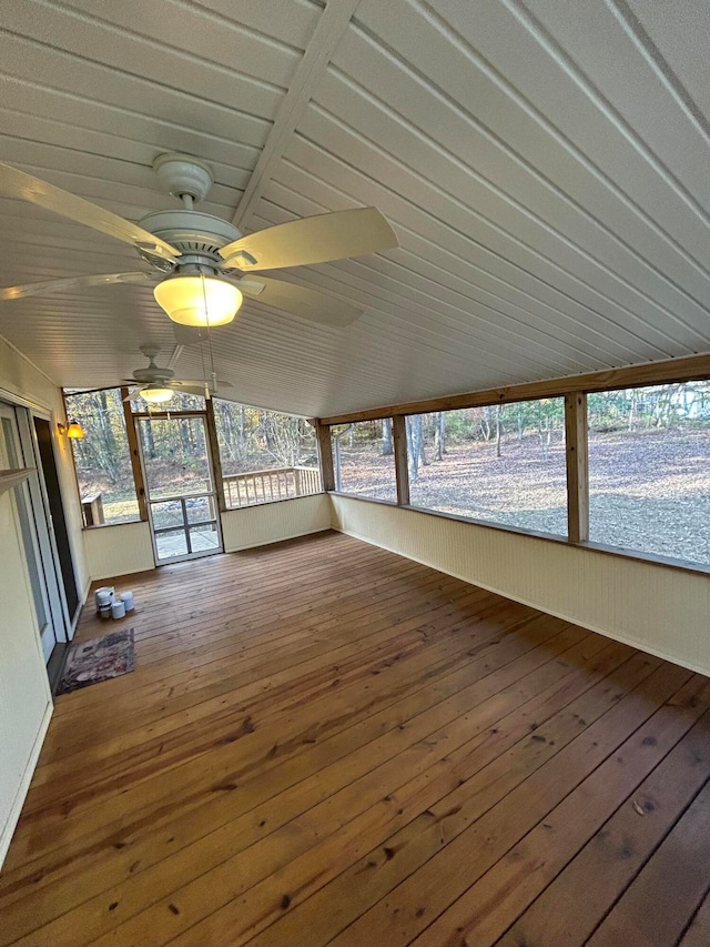 unfurnished sunroom featuring lofted ceiling, plenty of natural light, and ceiling fan