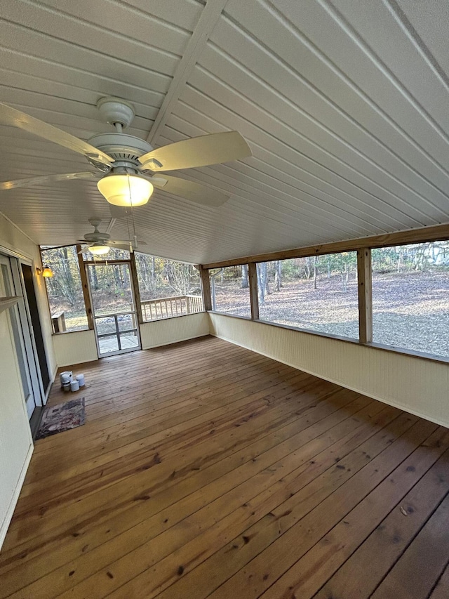 unfurnished sunroom featuring a ceiling fan, hardwood / wood-style flooring, and vaulted ceiling