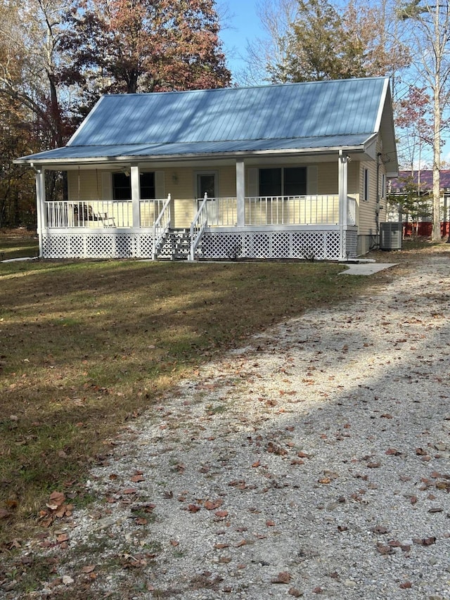 farmhouse-style home featuring a porch, driveway, metal roof, and a front lawn