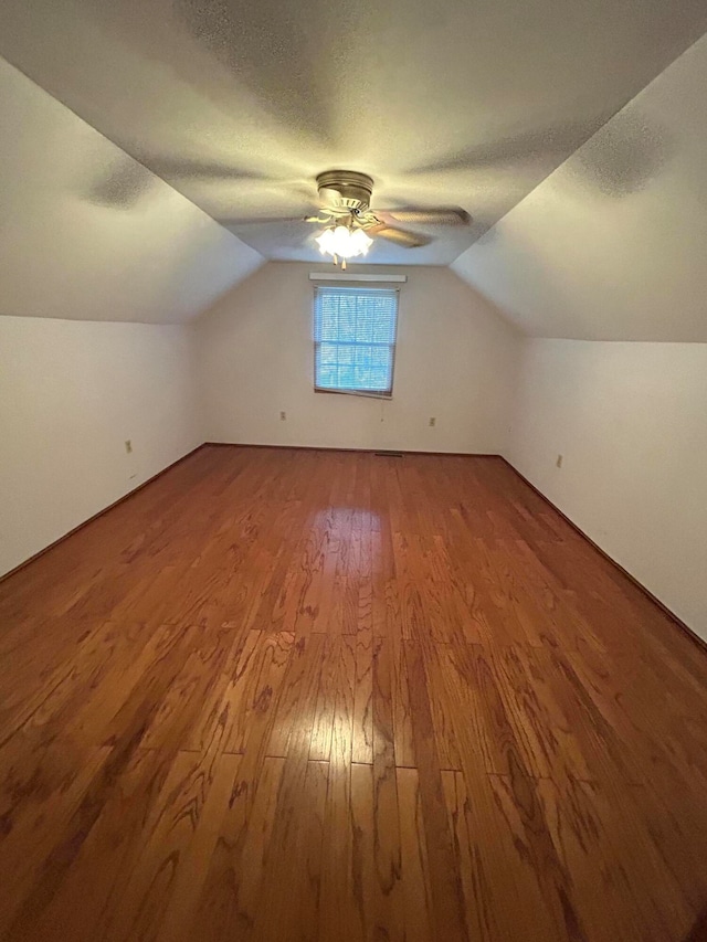 additional living space with lofted ceiling, hardwood / wood-style floors, a textured ceiling, and ceiling fan