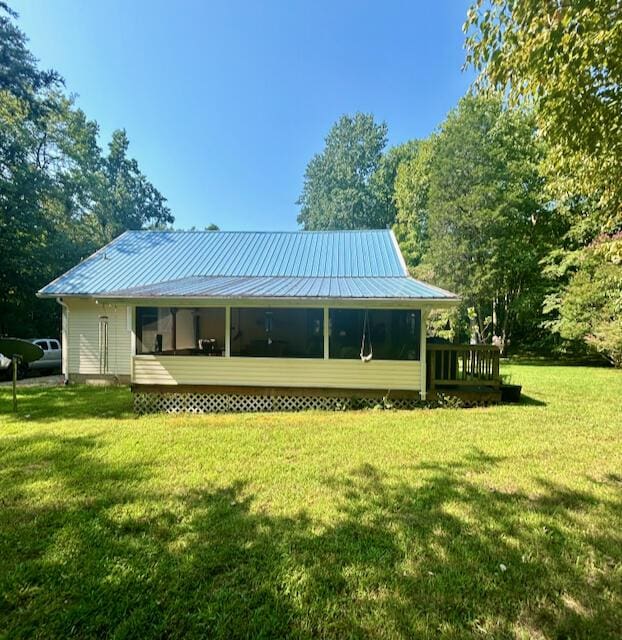 back of house featuring a lawn and metal roof