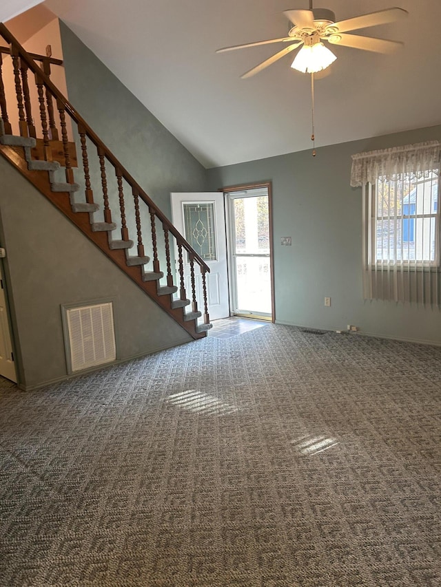 unfurnished living room with vaulted ceiling, carpet flooring, stairs, and ceiling fan
