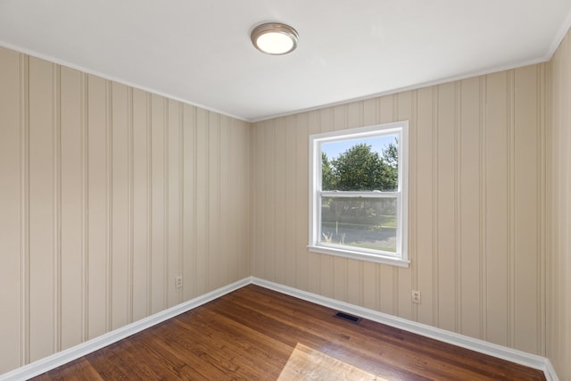 spare room featuring dark wood finished floors, visible vents, and baseboards