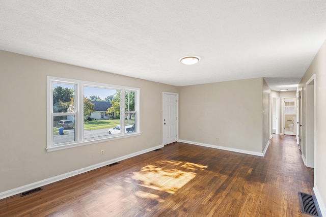 unfurnished room featuring dark wood-style floors, baseboards, and visible vents