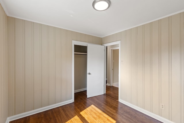 unfurnished bedroom featuring a closet, dark wood finished floors, and baseboards