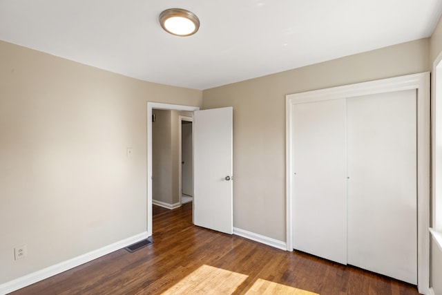 unfurnished bedroom with a closet, visible vents, baseboards, and wood finished floors