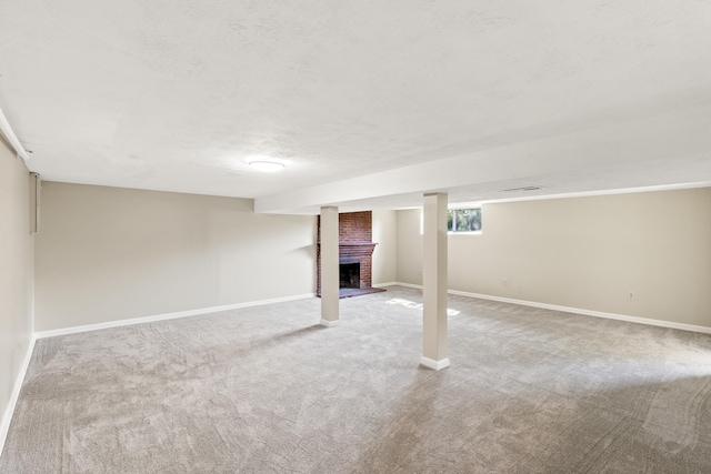 below grade area with light carpet, a fireplace, baseboards, and a textured ceiling