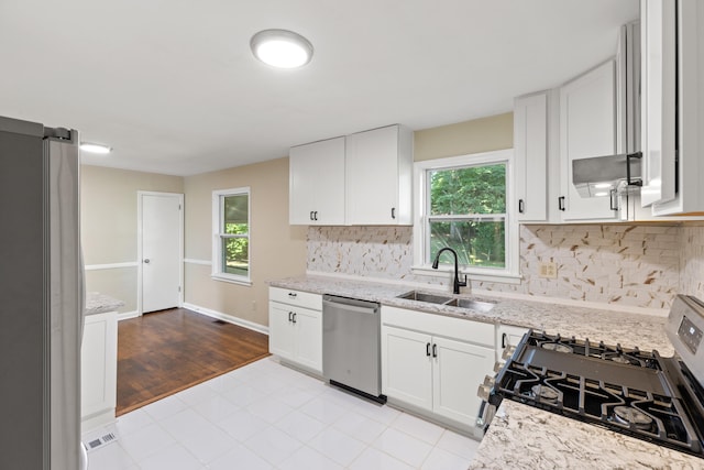 kitchen featuring a wealth of natural light, appliances with stainless steel finishes, white cabinets, and a sink