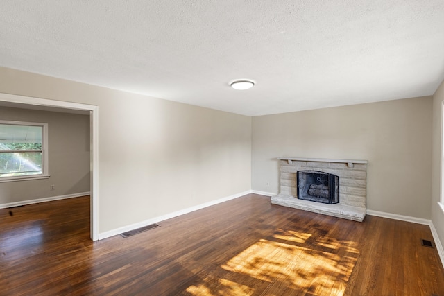 unfurnished living room featuring visible vents, a fireplace, baseboards, and wood finished floors