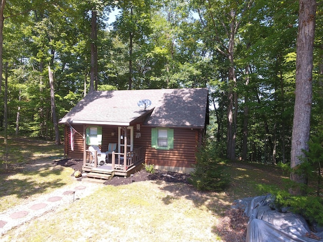 log home with covered porch and a front yard