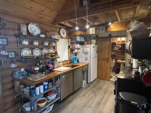 kitchen featuring a barn door, sink, rustic walls, light wood-type flooring, and white refrigerator