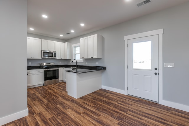 kitchen featuring dark wood-type flooring, sink, stainless steel appliances, kitchen peninsula, and white cabinets