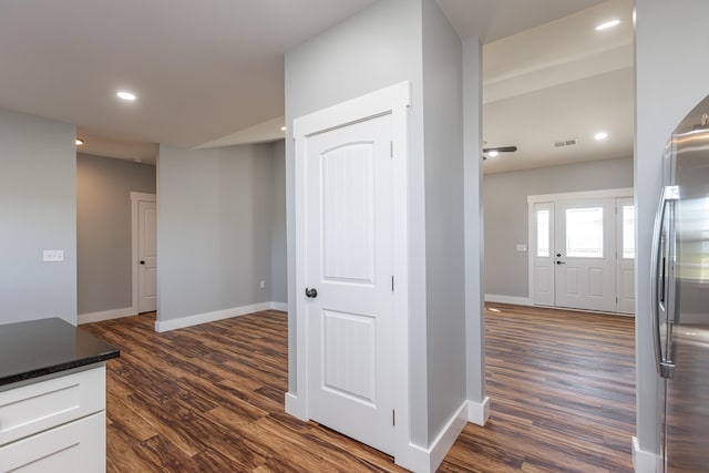 kitchen with stainless steel refrigerator, dark stone countertops, white cabinets, and dark hardwood / wood-style flooring