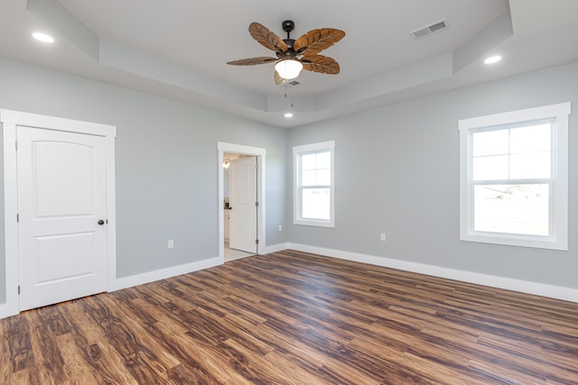 unfurnished room with a tray ceiling, hardwood / wood-style floors, and ceiling fan