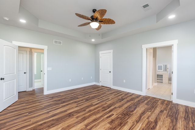 unfurnished bedroom featuring ceiling fan, light wood-type flooring, connected bathroom, and a tray ceiling