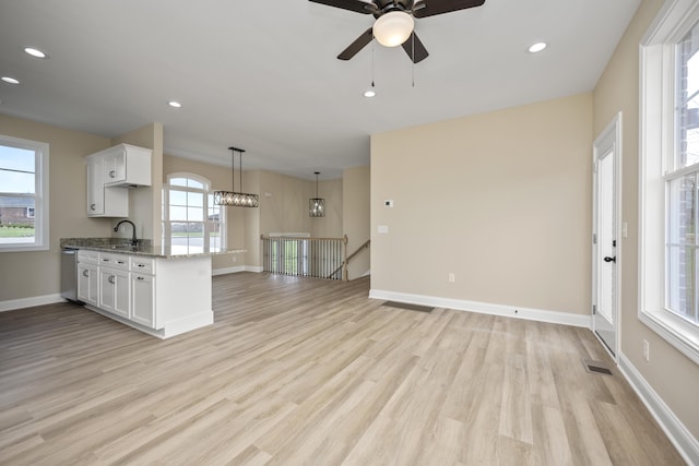 interior space featuring ceiling fan with notable chandelier, light wood-type flooring, sink, and a wealth of natural light