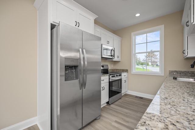 kitchen featuring light stone countertops, stainless steel appliances, sink, white cabinets, and light hardwood / wood-style floors