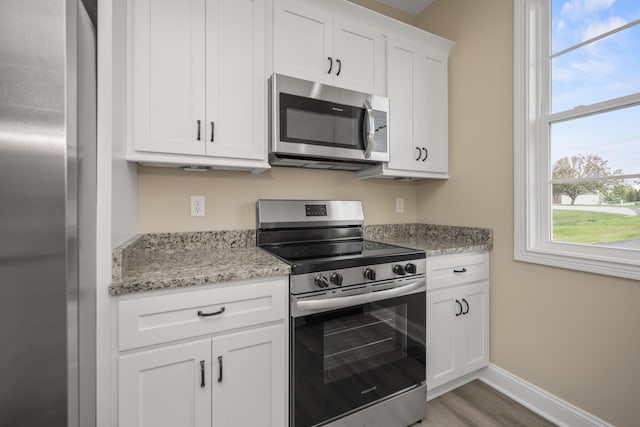 1814 Adkinson Dr, Richmond, KY 40475 - kitchen featuring appliances with stainless steel finishes, white cabinetry, light stone counters, baseboards, and light wood-style flooring