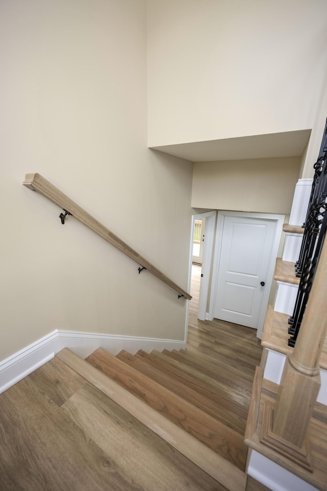 stairway with a high ceiling and hardwood / wood-style flooring