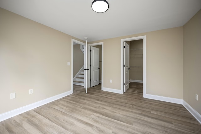 unfurnished bedroom featuring light wood-type flooring, a spacious closet, and a closet