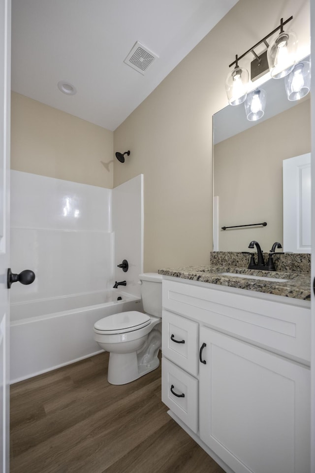 full bathroom with bathing tub / shower combination, hardwood / wood-style floors, vanity, and toilet