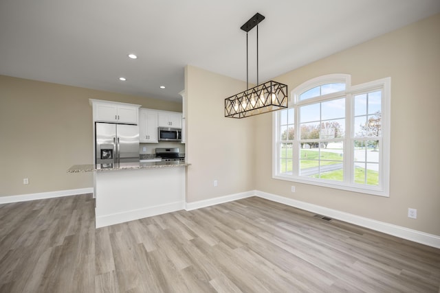 kitchen featuring a wealth of natural light, white cabinetry, light wood-type flooring, and appliances with stainless steel finishes