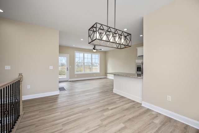 unfurnished living room featuring ceiling fan and light wood-type flooring