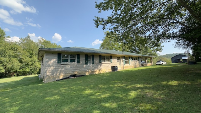 rear view of property featuring a lawn and central AC