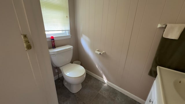 bathroom with vanity, toilet, wood walls, and tile patterned floors