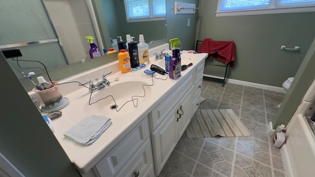 bathroom with plenty of natural light, vanity, toilet, and tile patterned floors