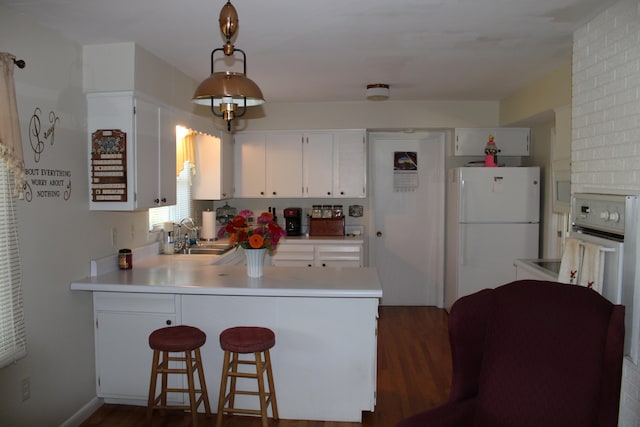 kitchen with white fridge, dark hardwood / wood-style flooring, a kitchen bar, kitchen peninsula, and sink