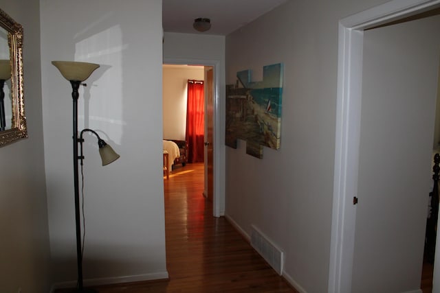 hallway featuring wood finished floors, visible vents, and baseboards