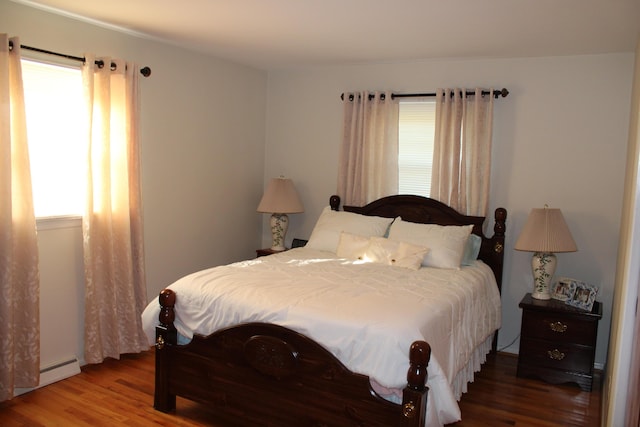 bedroom featuring a baseboard heating unit and wood finished floors