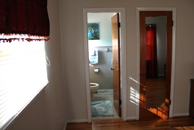 corridor with tile walls, a wealth of natural light, and hardwood / wood-style floors