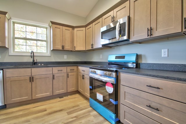 kitchen with sink, vaulted ceiling, stainless steel appliances, and light hardwood / wood-style floors