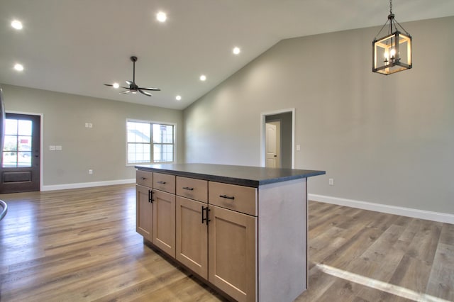 kitchen featuring ceiling fan with notable chandelier, a center island, light hardwood / wood-style floors, and decorative light fixtures