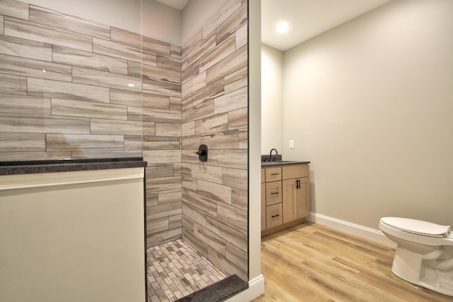 bathroom featuring vanity, toilet, hardwood / wood-style floors, and a tile shower