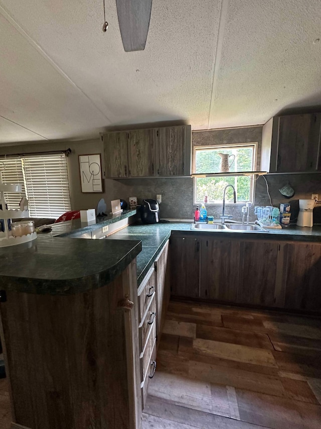 kitchen featuring kitchen peninsula, dark hardwood / wood-style floors, sink, and backsplash