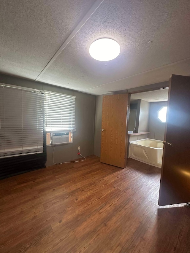 interior space with cooling unit, multiple windows, dark hardwood / wood-style floors, and a textured ceiling