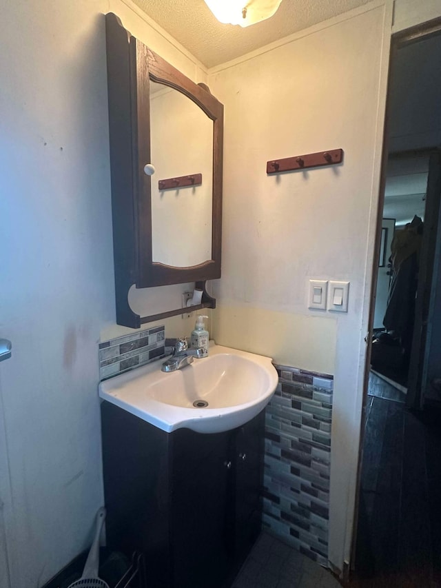 bathroom with vanity, a textured ceiling, and decorative backsplash