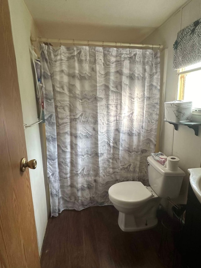 bathroom with hardwood / wood-style floors, walk in shower, and toilet