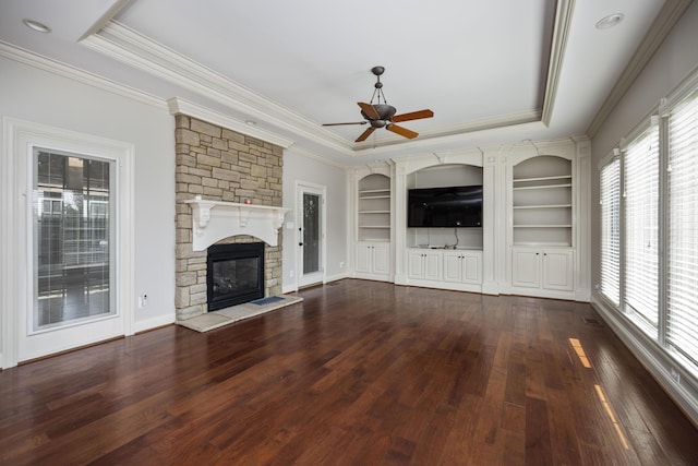 unfurnished living room featuring built in shelves, dark wood-style flooring, a fireplace, and a raised ceiling