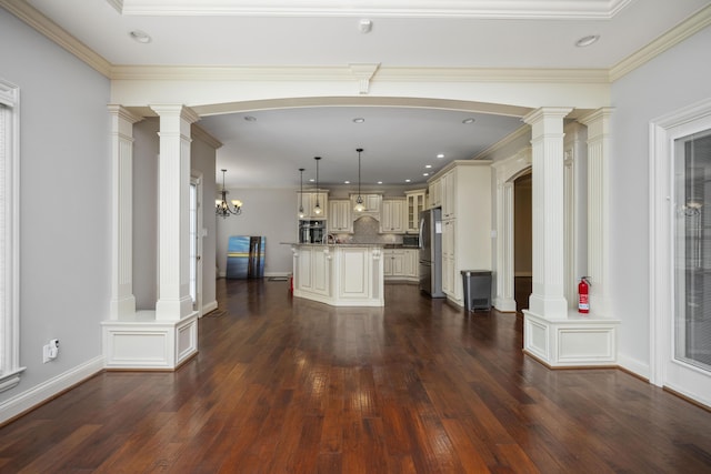 kitchen featuring tasteful backsplash, decorative columns, dark wood finished floors, appliances with stainless steel finishes, and cream cabinetry