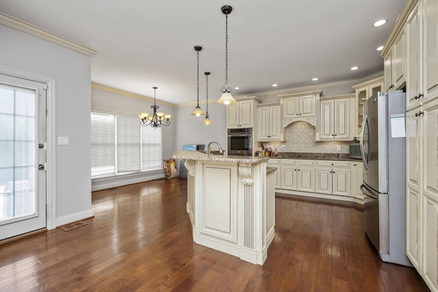 kitchen featuring ornamental molding, appliances with stainless steel finishes, cream cabinetry, backsplash, and dark wood-style floors