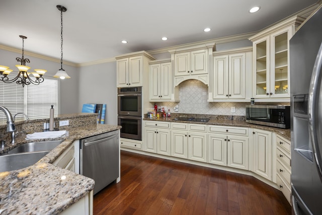 kitchen with cream cabinets, crown molding, appliances with stainless steel finishes, and a sink