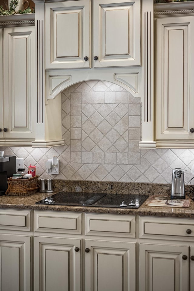 kitchen featuring dark stone counters, cream cabinetry, and tasteful backsplash