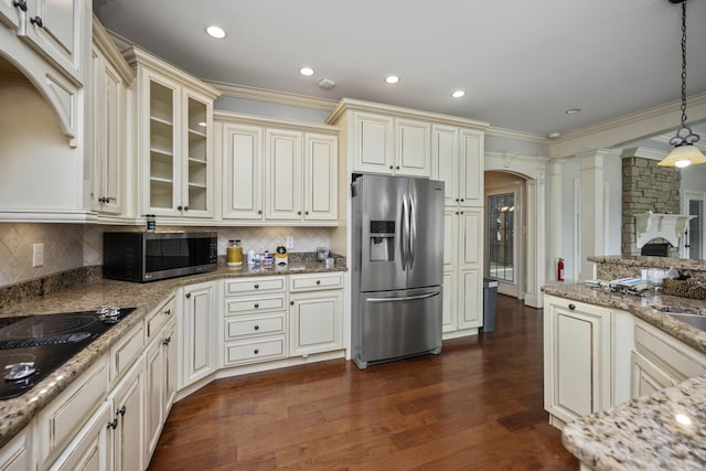 kitchen with arched walkways, stainless steel appliances, cream cabinets, and ornate columns