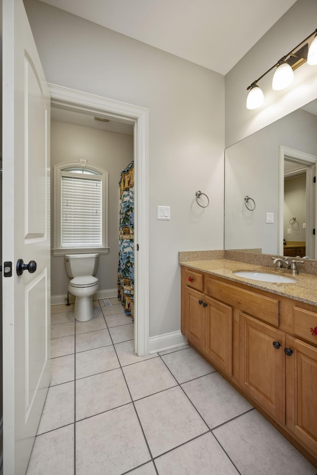 bathroom with tile patterned flooring, baseboards, vanity, and toilet